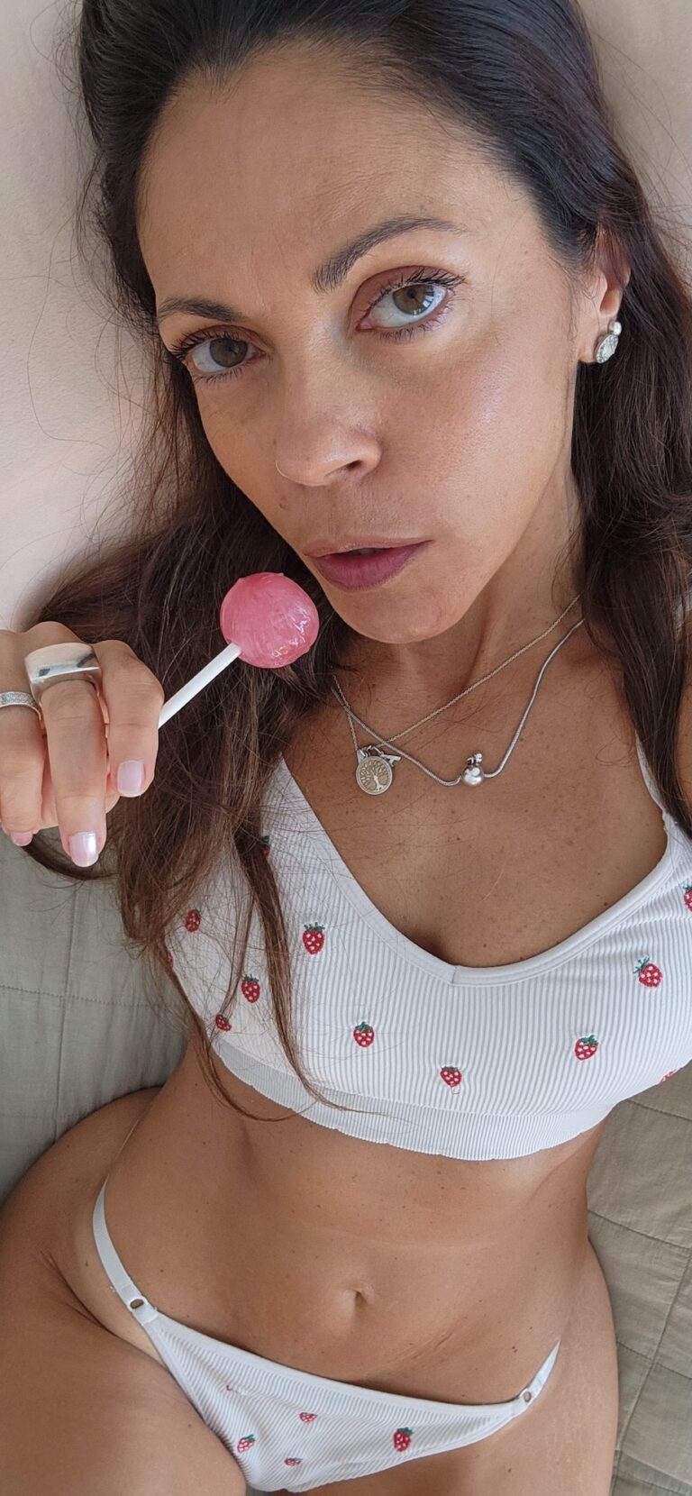 Angelina lying on bed holding a lollipop